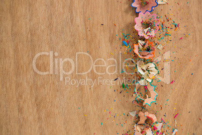 Colored pencil shavings on wooden background