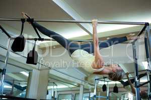 Determined woman performing stretching exercise on pilates cadillac