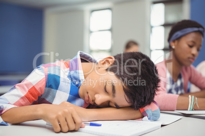 Tired schoolboy sleeping in classroom