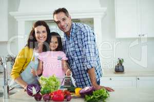 Portrait of parents and daughter preparing salad in kitchen