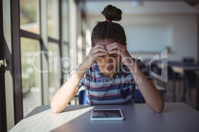 Worried schoolgirl sitting in classroom