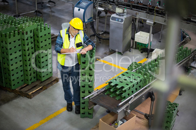 Male factory worker maintaining record on clipboard