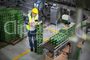 Male factory worker maintaining record on clipboard