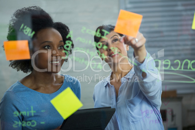 Female graphic designer pointing to the sticky notes on the glass
