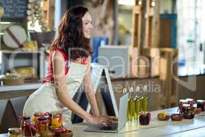 Female shop assistant using laptop at the counter