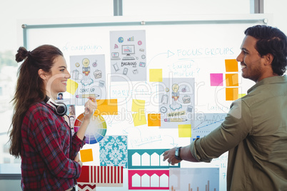 Male and female graphic designers discussing over sticky notes