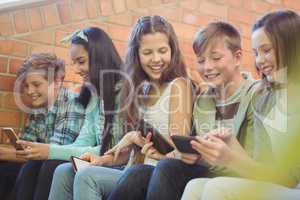 Group of smiling school friends sitting on staircase using mobile phone