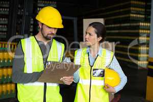 Factory workers discussing inventory over clipboard