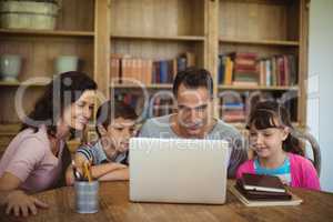 Parents and kids using laptop on table in study room