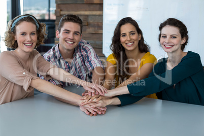 Group of smiling business executives forming hand stack in office