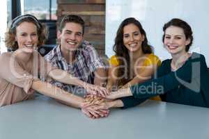 Group of smiling business executives forming hand stack in office