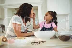 Daughter feeding her mother while preparing cookies
