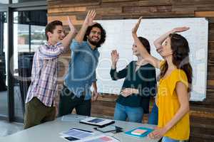 Business executives giving high five in office
