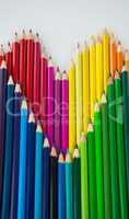 Colored pencils arranged in heart shape on white background