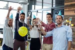 Businesspeople showing glasses of champagne in office