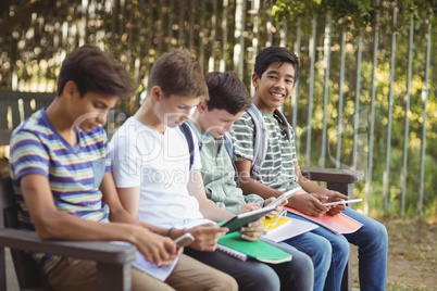 School kids using mobile phone and digital tablet on bench