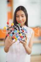 Schoolgirl experimenting molecule model in laboratory at school