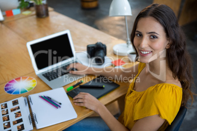 Smiling female graphic designer using laptop