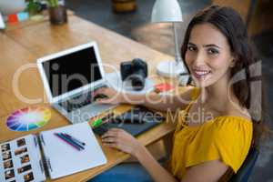 Smiling female graphic designer using laptop