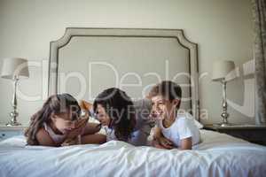 Mother and kids lying on bed in bedroom