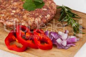 Beef patty and ingredients on wooden tray