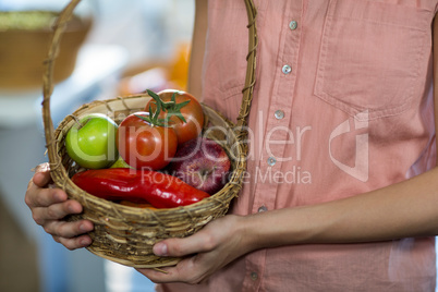 Woman holding a basket with variety of fruits and vegetables