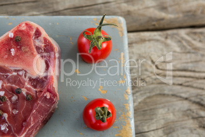 Sirloin steak and cherry tomatoes on board against wooden background