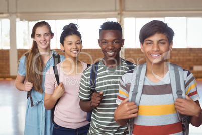 Portrait of happy students standing with schoolbags in campus