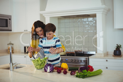 Mother and son mixing the salad in kitchen