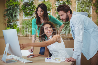 Team of graphic designers discussing over computer at desk