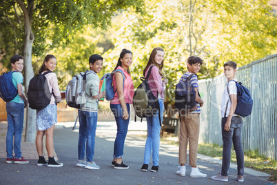 Portrait of happy students standing with books on road