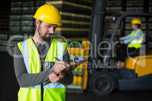 Factory worker writing on clipboard