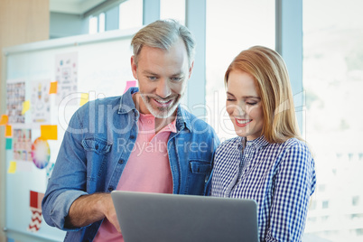 Male and female business executives using laptop