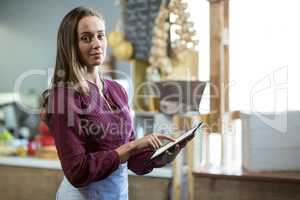 Portrait of smiling female staff using digital tablet at counter