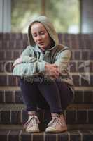 Sad schoolgirl sitting alone on staircase