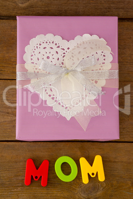 Gift box with alphabets reading mom against wooden background