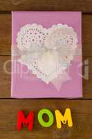 Gift box with alphabets reading mom against wooden background