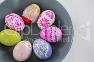 Bowl with painted Easter eggs on white background