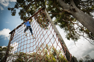 Woman climbing a net during obstacle course