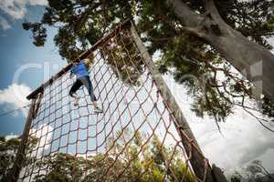 Woman climbing a net during obstacle course