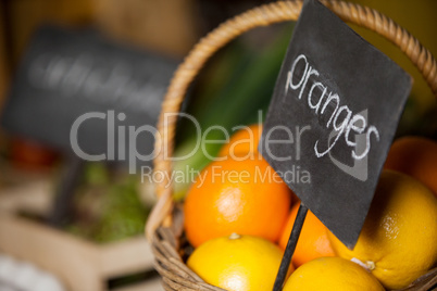 Close-up of fresh oranges in wicker basket with placard