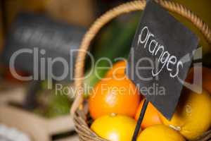 Close-up of fresh oranges in wicker basket with placard