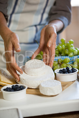 Mid section of female staff arranging cheese at counter