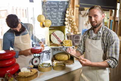 Salesman writing on clipboard at counter in grocery shop