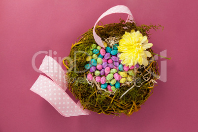 Colorful easter eggs in wicker basket with a flower