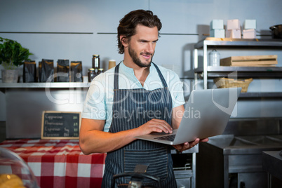 Male staff using laptop at counter