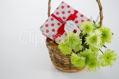 Gift box and bunch of yellow flowers in wicker basket with happy mothers day tag