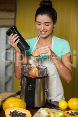 Smiling shop assistant preparing juice