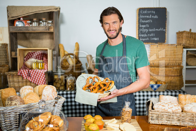 Portrait of male staff holding basket of pretzel at counter