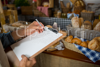 Salesman writing on clipboard at counter